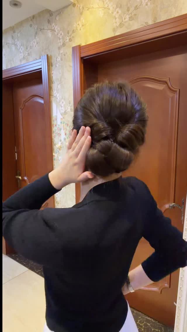 Woman with an intricate brown updo hairstyle featuring coiled buns from behind.