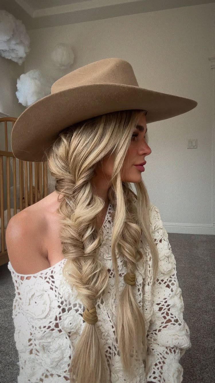 Woman with blonde hair in two loose braids wearing a tan hat.