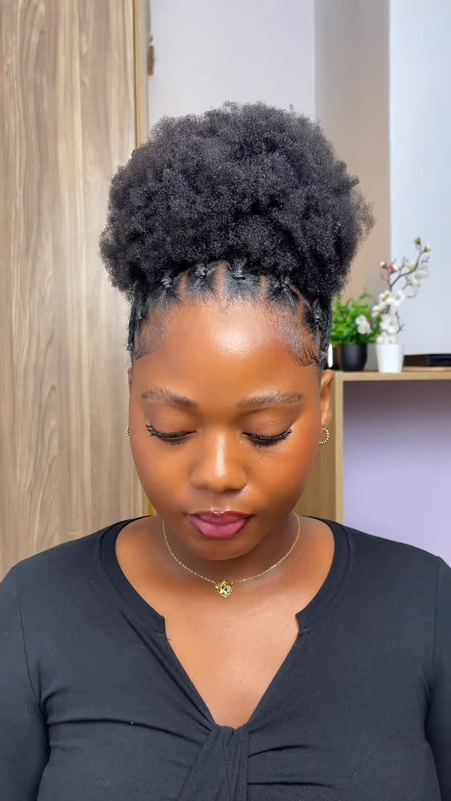 23 Hairstyles with Black Hair: Braids, Cuts, and Buns 6 Woman with a high afro puff hairstyle and small braids at the base.