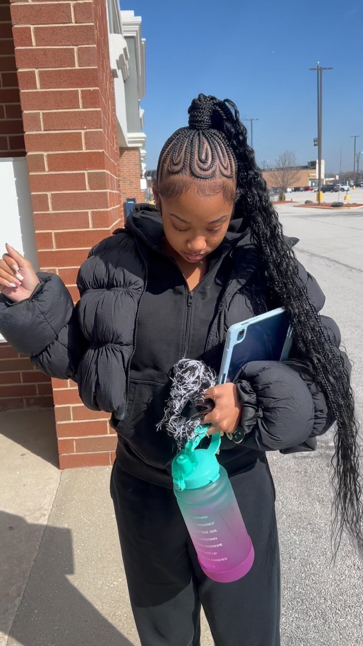 23 Hairstyles with Black Hair: Braids, Cuts, and Buns 9 Woman with long black braided hair styled in a high braided ponytail.