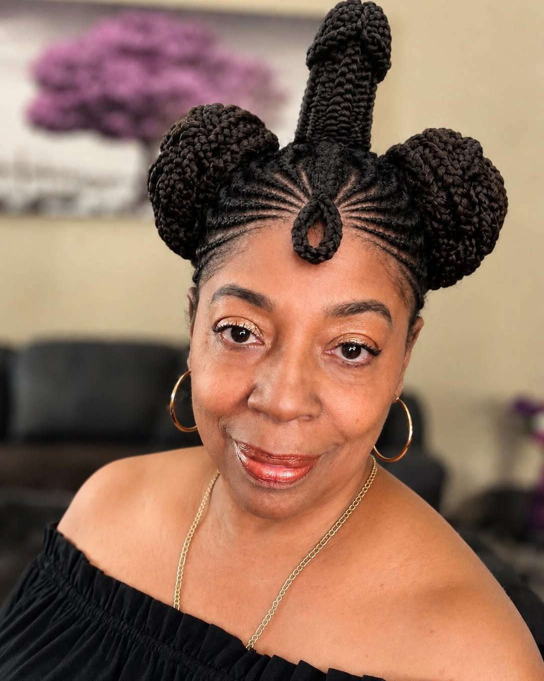 23 Hairstyles with Black Hair: Braids, Cuts, and Buns 11 Woman with black hair styled in three braided buns and cornrows.