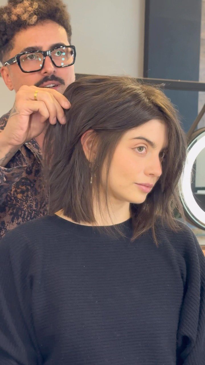 23 Hairstyles with Black Hair: Braids, Cuts, and Buns 17 Woman with a dark brown choppy lob haircut being styled in a salon.