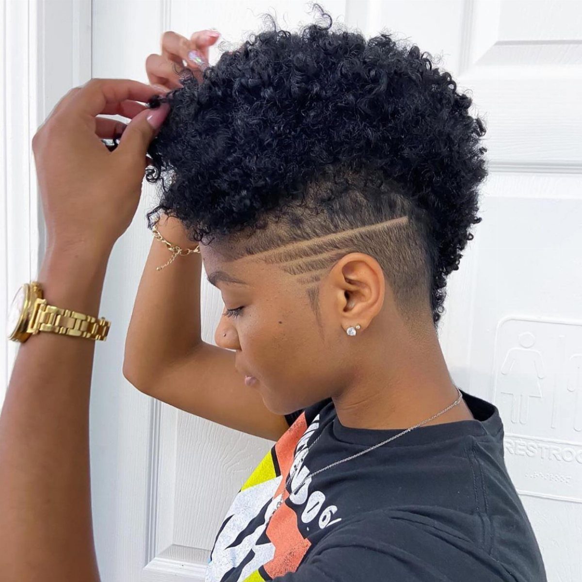 23 Hairstyles with Black Hair: Braids, Cuts, and Buns 14 Person with a curly faux hawk and shaved sides with carved line designs.