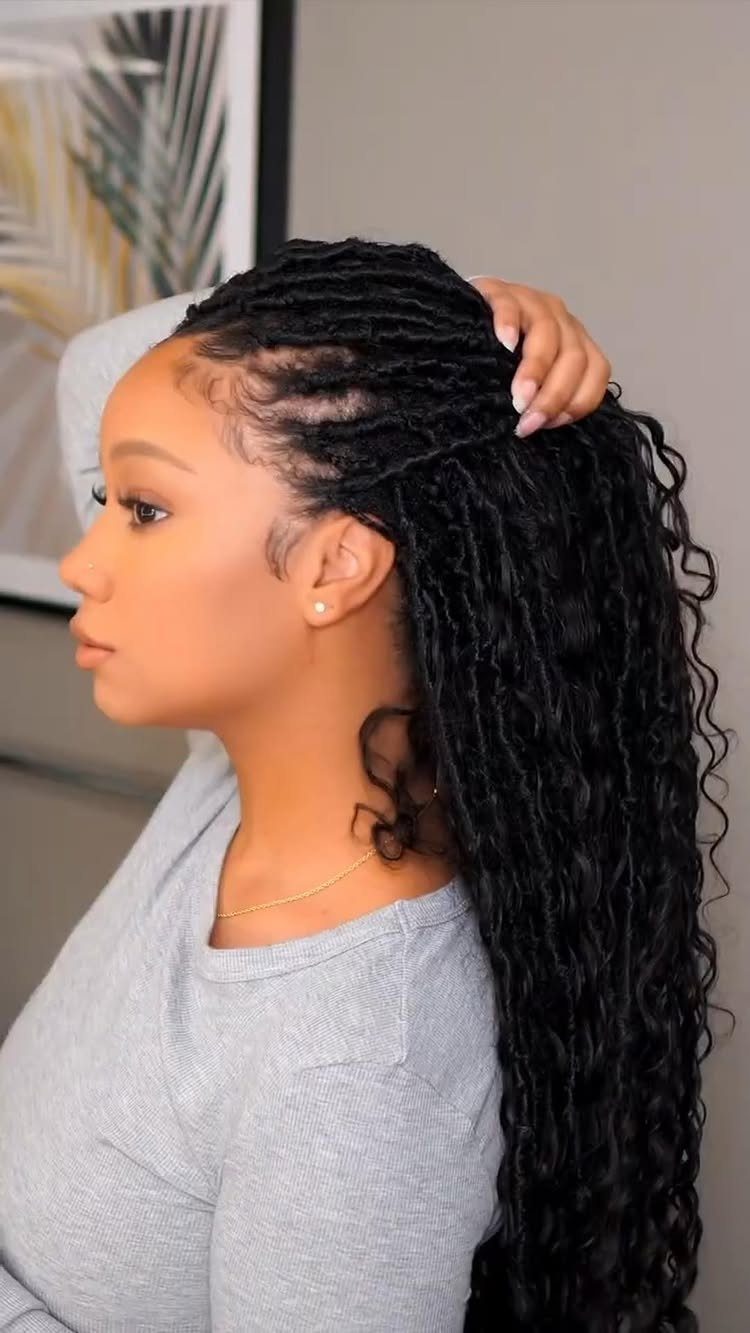 23 Hairstyles with Black Hair: Braids, Cuts, and Buns 3 Woman with long black faux locs ending in curls, wearing a grey shirt.