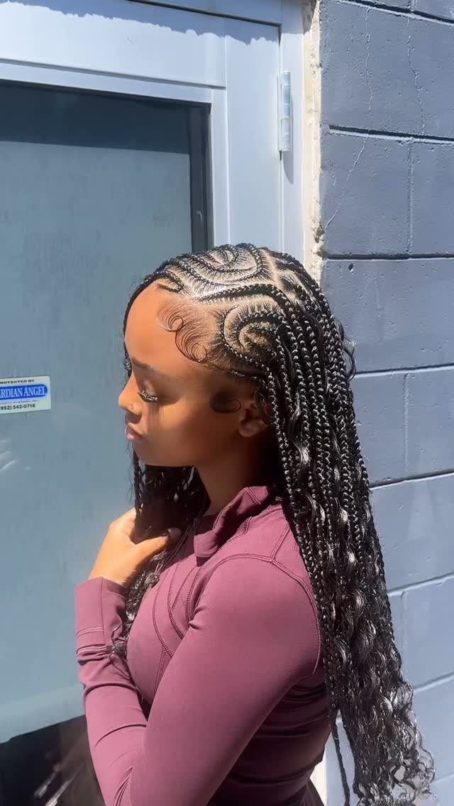 23 Hairstyles with Black Hair: Braids, Cuts, and Buns 22 Woman with long black goddess braids and curly ends wearing a purple shirt.