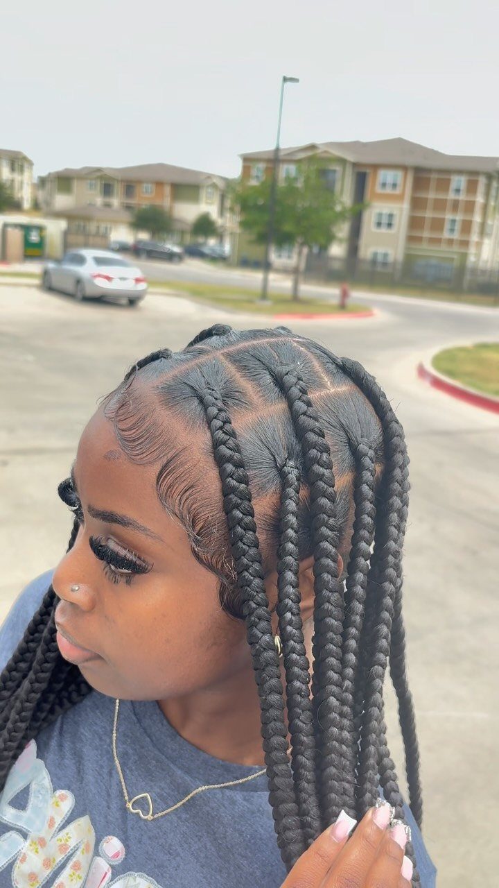 23 Hairstyles with Black Hair: Braids, Cuts, and Buns 2 Woman with long black knotless braids posing outdoors in a residential neighborhood.