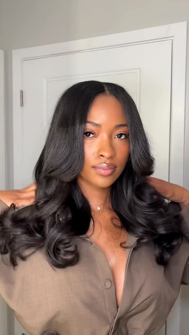 23 Hairstyles with Black Hair: Braids, Cuts, and Buns 18 Woman with long wavy black hair styled in a middle part weave.