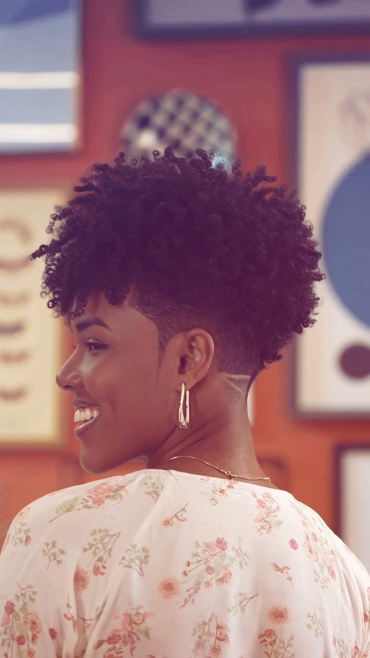 23 Hairstyles with Black Hair: Braids, Cuts, and Buns 15 Woman with a tapered natural haircut and curly black hair smiling in profile.