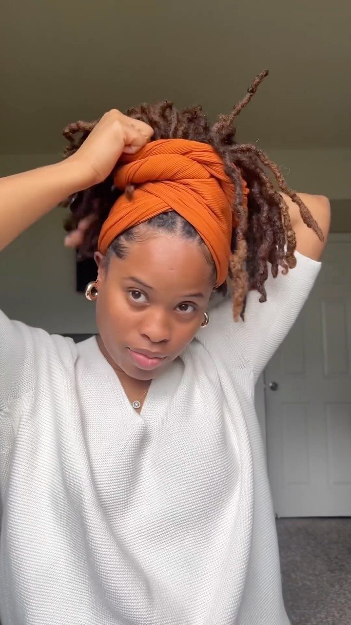 Healthy Hair Styles: 17 Protective Ideas for Natural Hair 10 Woman with brown locs wearing an orange fabric headwrap and white sweater.