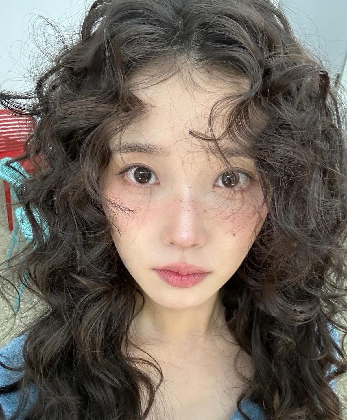 16 Homecoming Hair Curly Ideas: Buns, Braids, and Puffs 16 Woman with voluminous dark brown curly hair framing her face in a portrait.