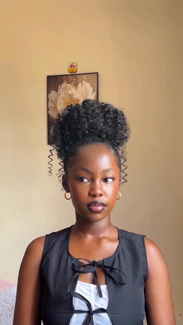 16 Homecoming Hair Curly Ideas: Buns, Braids, and Puffs 10 Woman with dark curly hair styled in a high voluminous puff hairstyle.