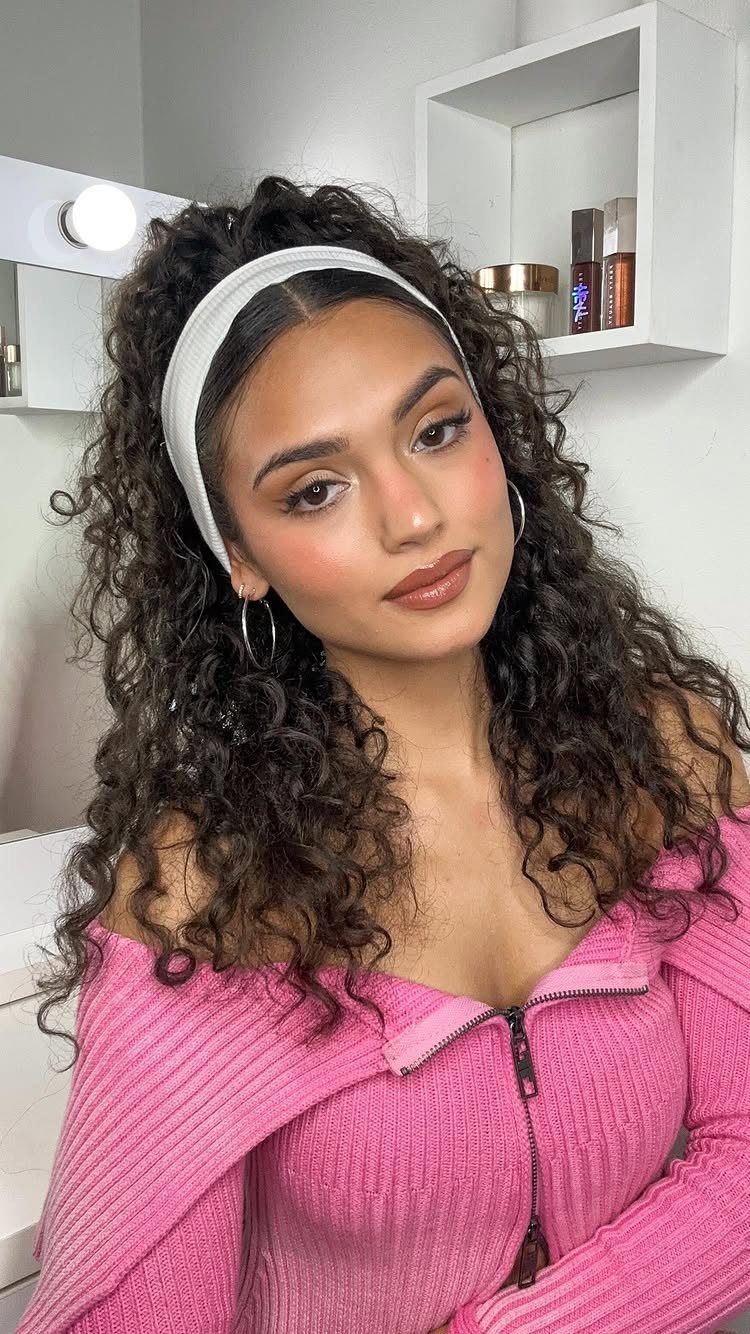 16 Homecoming Hair Curly Ideas: Buns, Braids, and Puffs 15 Young woman with long dark curly hair wearing a white headband and pink top