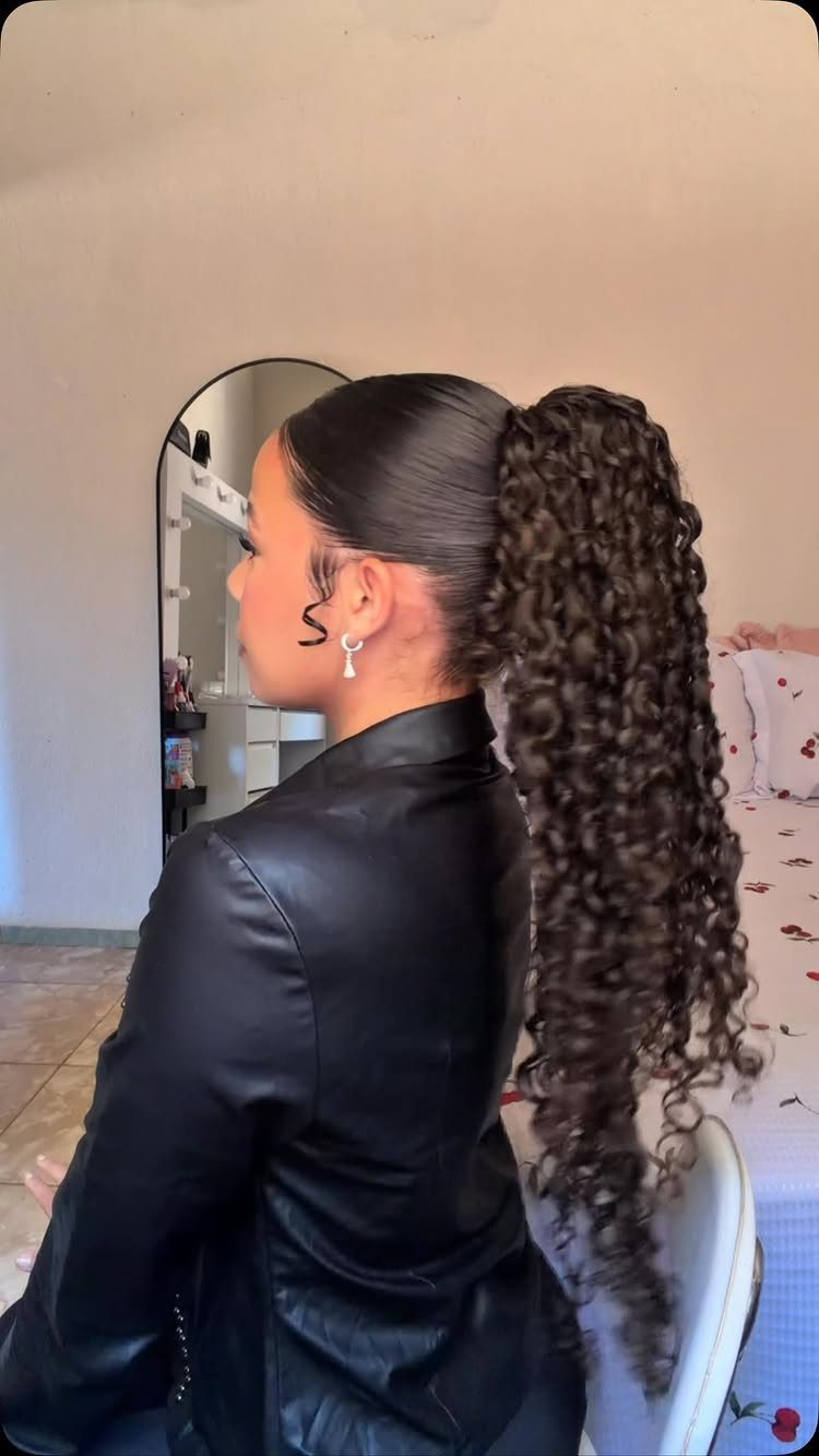 16 Homecoming Hair Curly Ideas: Buns, Braids, and Puffs 5 Woman with a high, voluminous curly ponytail wearing a black leather jacket.