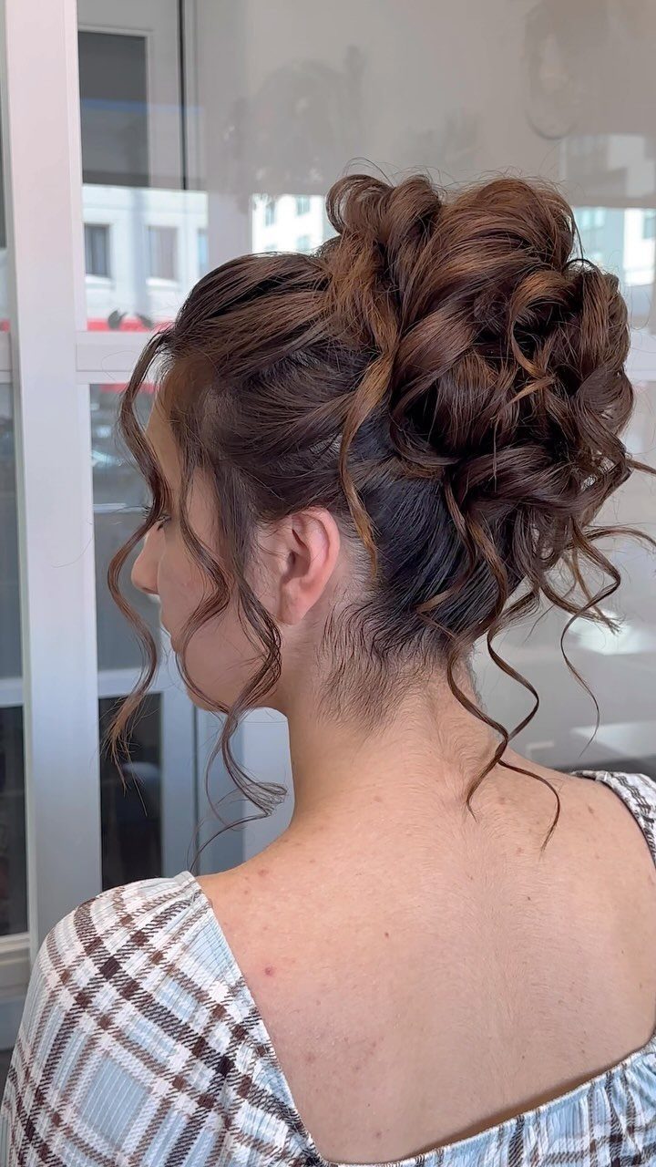 16 Homecoming Hair Curly Ideas: Buns, Braids, and Puffs 1 Woman with brown curly hair styled in a voluminous messy bun updo.