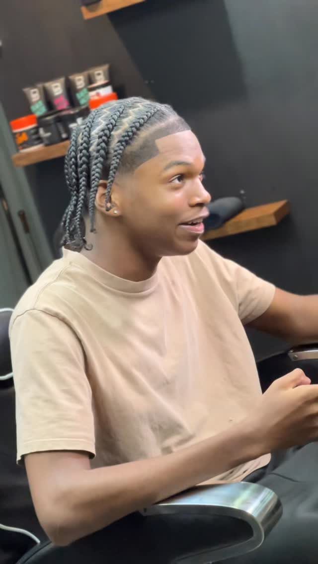6 Knotless Braids Men Can Wear: Styles With Fades and Color 4 Man with greyish-blue knotless braids and a sharp hairline sitting in a salon chair.