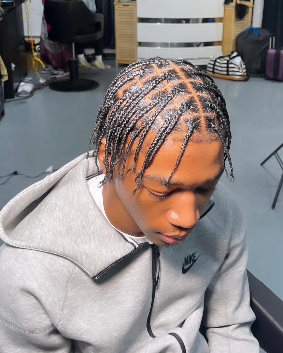 6 Knotless Braids Men Can Wear: Styles With Fades and Color 1 Young man with black box braids wearing a grey Nike zip-up hoodie.