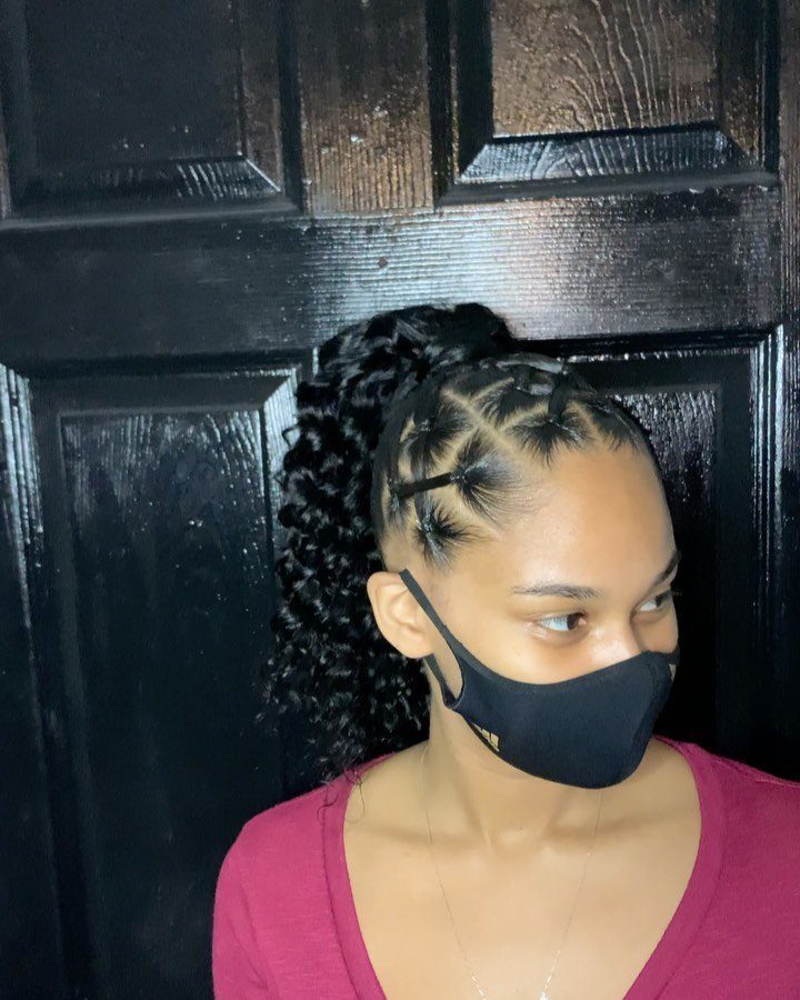 10 Little Rubber Bands for Hairstyles Kids Love 8 Woman with curly hair in a high ponytail secured with small black rubber bands.