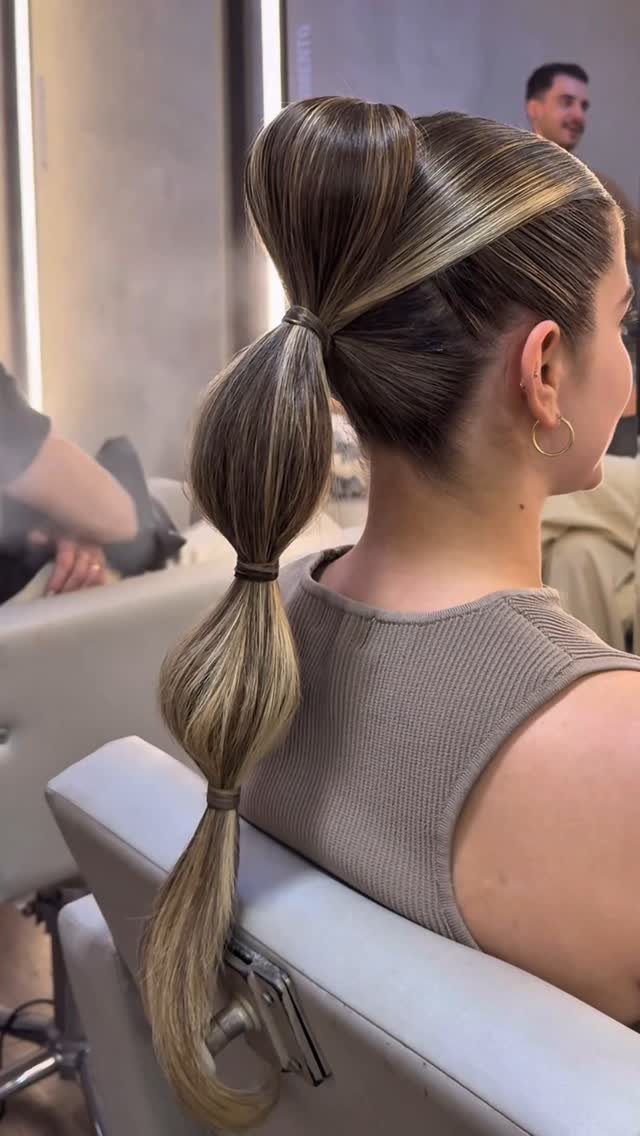 16 Long Hair Hairstyles for Party Looks You Can Copy 4 Woman with a high bubble braid ponytail and a sleek top bun in salon