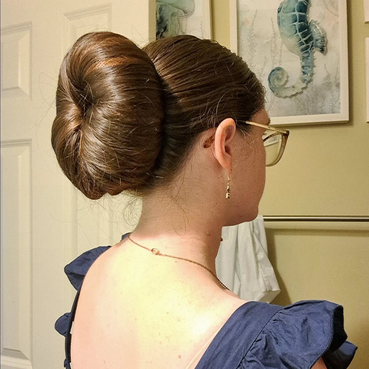 16 Long Hair Hairstyles for Party Looks You Can Copy 10 Woman with brown hair styled in a large, smooth, circular donut bun.