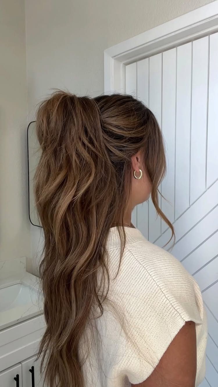 16 Long Hair Hairstyles for Party Looks You Can Copy 3 Woman with long wavy brown hair in a messy half-up ponytail wearing white knit.