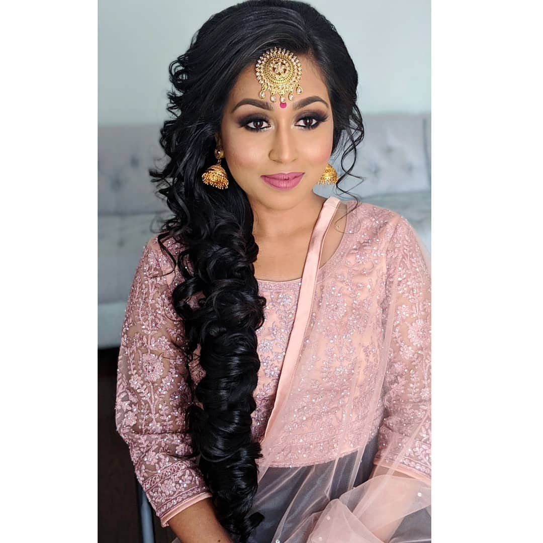 16 Long Hair Hairstyles for Party Looks You Can Copy 12 Woman with long dark curly hair swept to the side wearing traditional Indian attire