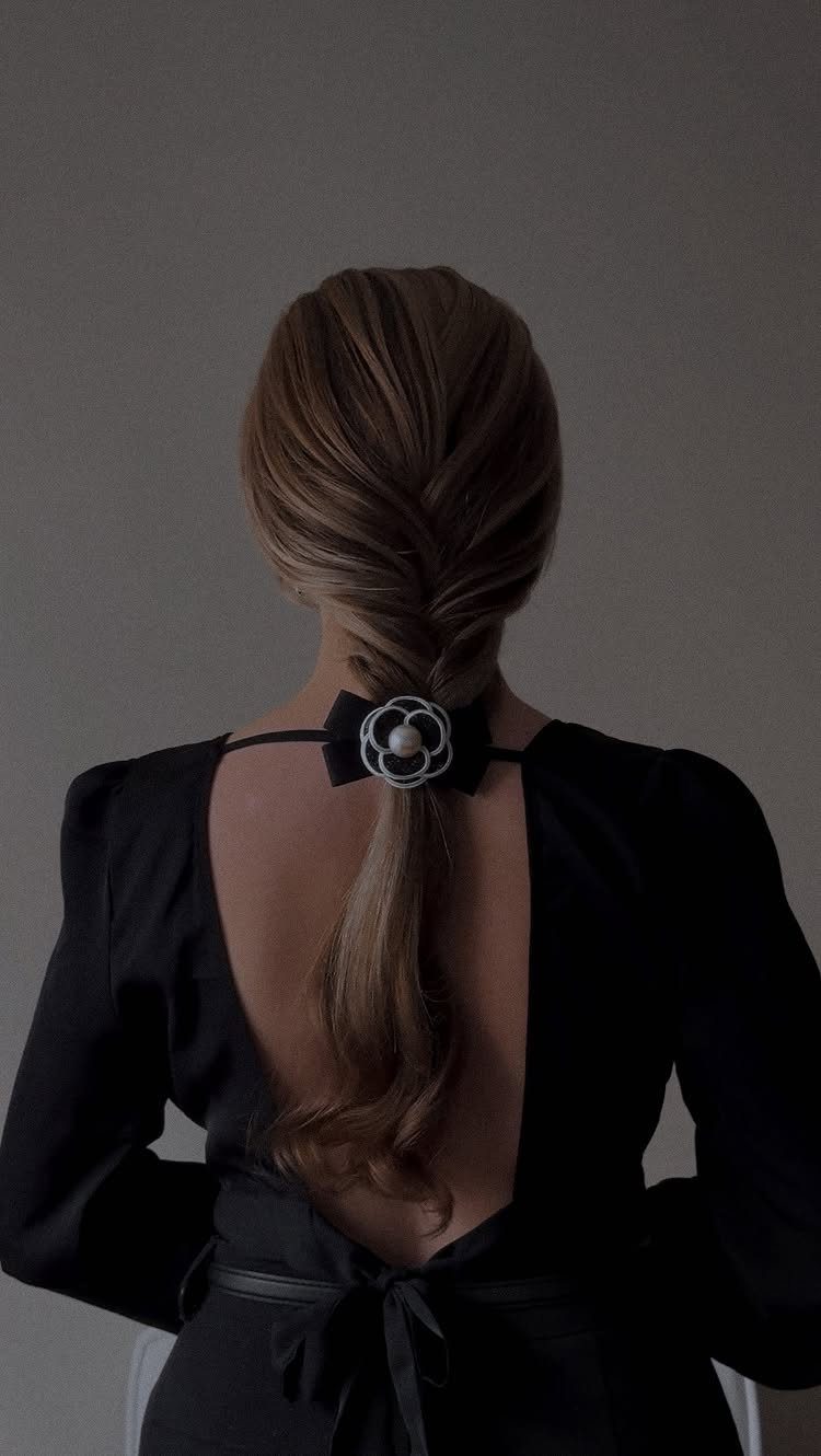16 Long Hair Hairstyles for Party Looks You Can Copy 5 Blonde hair styled in a twisted braid with a black floral bow accessory.