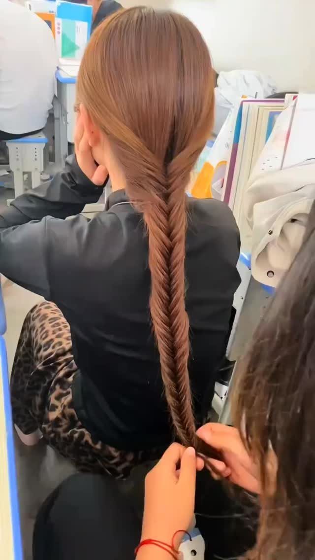 20 Long Hair Hairstyles for Work, From Buns to Braids 2 Woman with long brown hair being styled into a detailed fishtail braid.