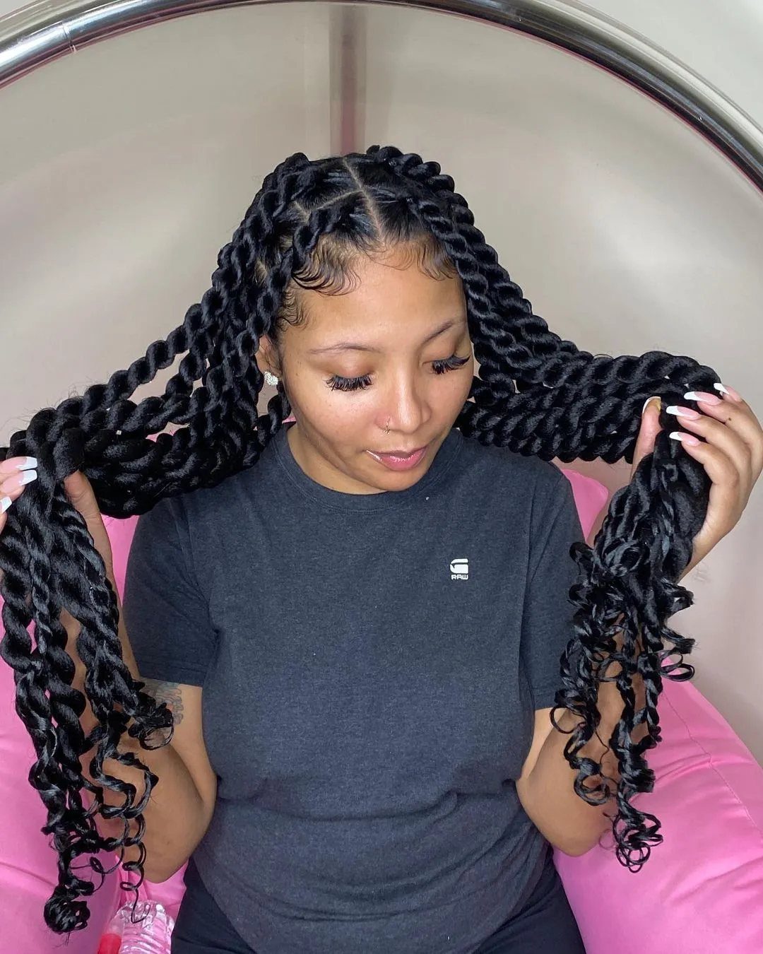20 Long Hair Hairstyles for Work, From Buns to Braids 10 Woman with long black twisted hair wearing a grey t-shirt sitting in chair