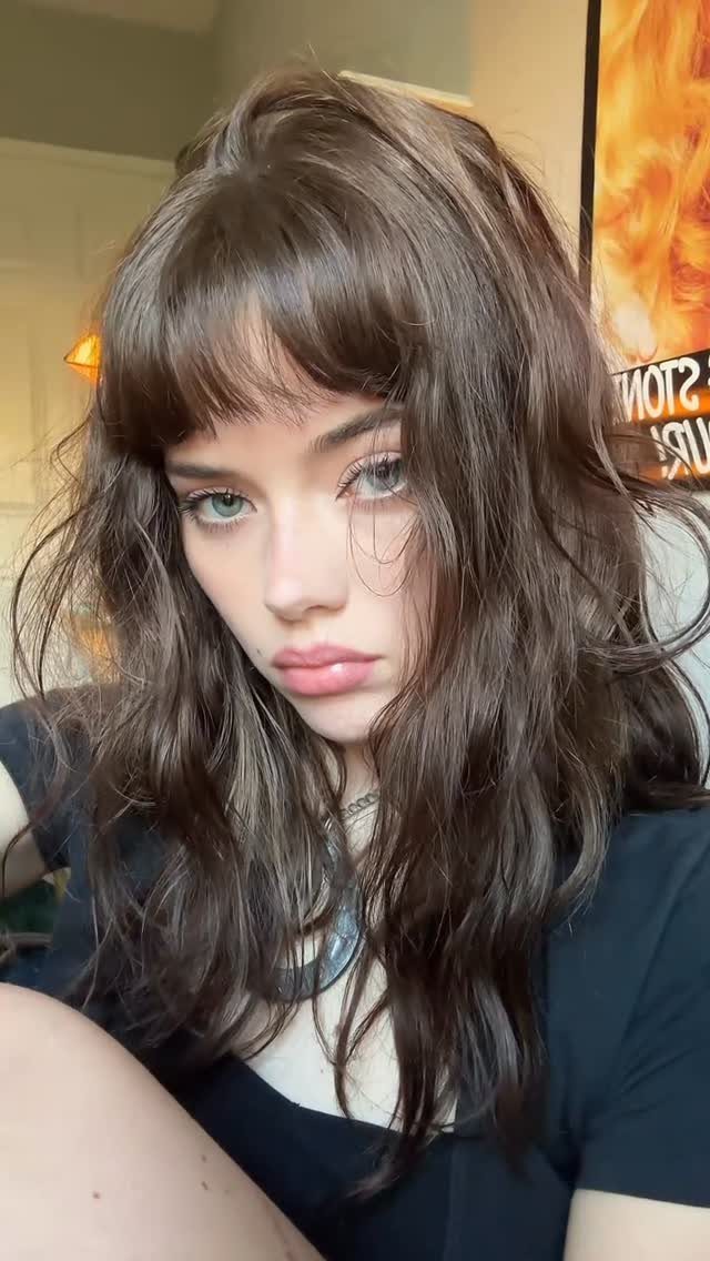 Long Hair Without Layers: 9 One-Length Styles to Try 4 Woman with long wavy brown hair and full bangs wearing a black top