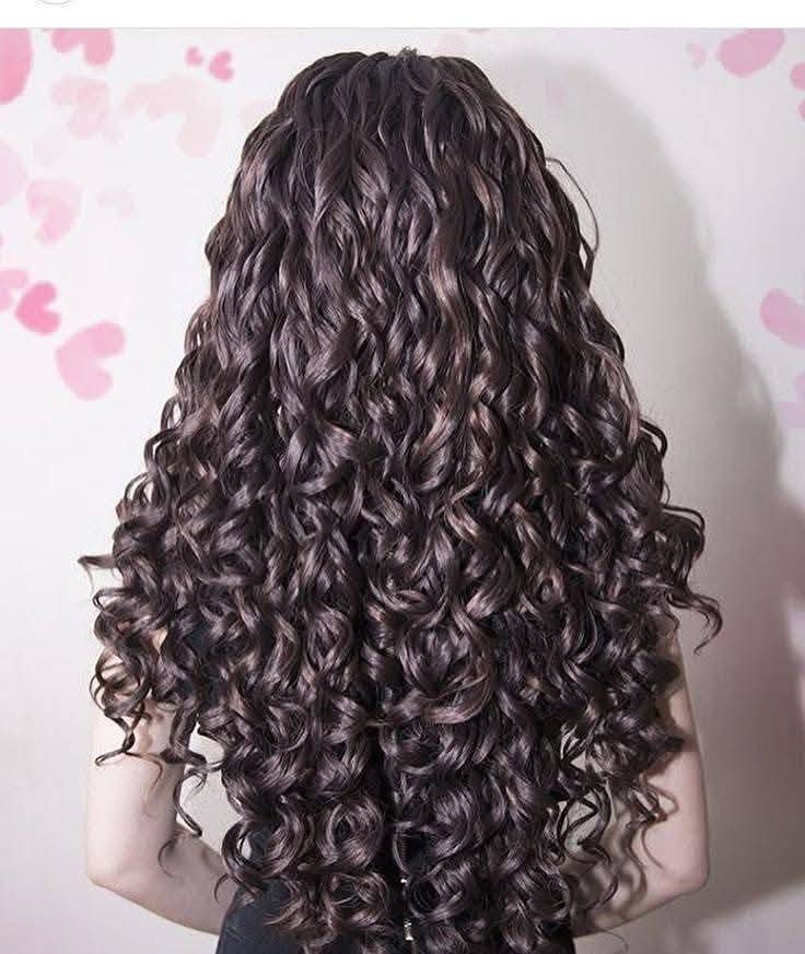 Long Hair Without Layers: 9 One-Length Styles to Try 8 Long dark brown curly hair seen from behind against a heart-patterned wall