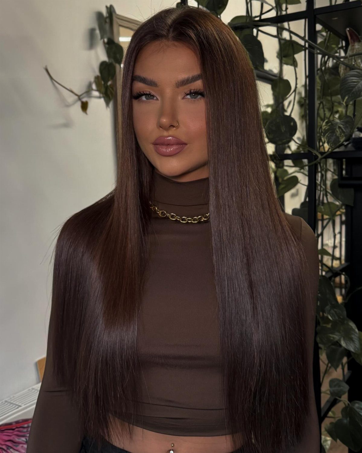Long Hair Without Layers: 9 One-Length Styles to Try 3 Woman with long straight dark brown hair and a polished middle parting.