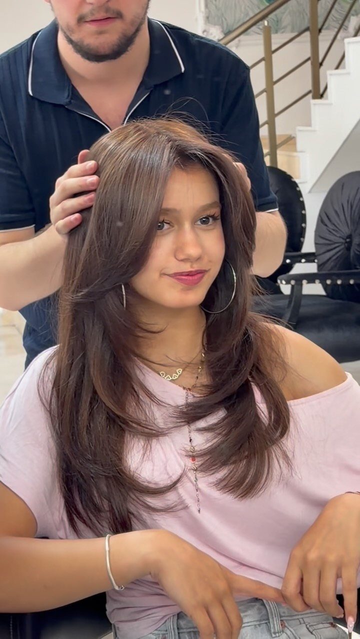 11 Long Loose Hair Ideas for Every Style and Texture 9 Woman with a brown butterfly haircut featuring voluminous feathery layers in a salon