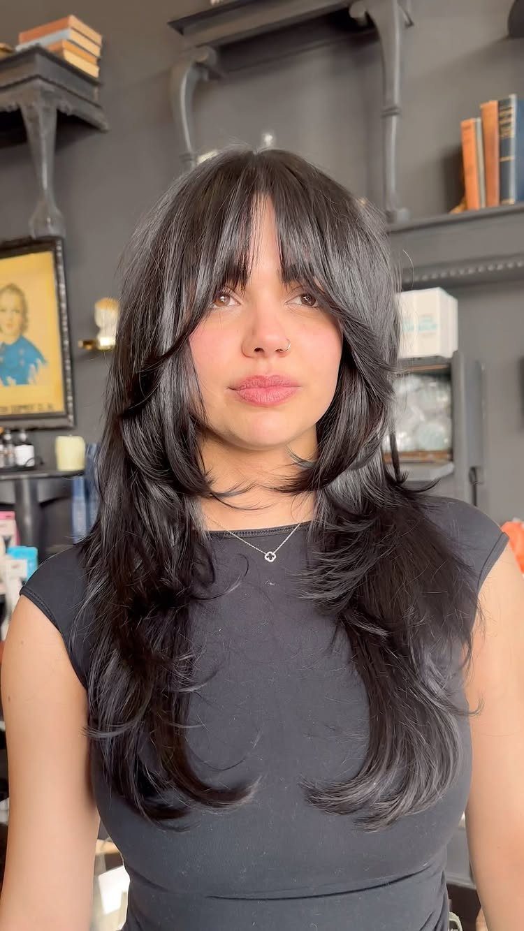 11 Long Loose Hair Ideas for Every Style and Texture 10 Woman with long layered black hair and bangs wearing a black sleeveless top.