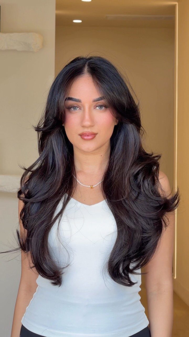 11 Long Loose Hair Ideas for Every Style and Texture 11 Woman with voluminous dark brown hair in a smooth blow-out with face-framing layers.