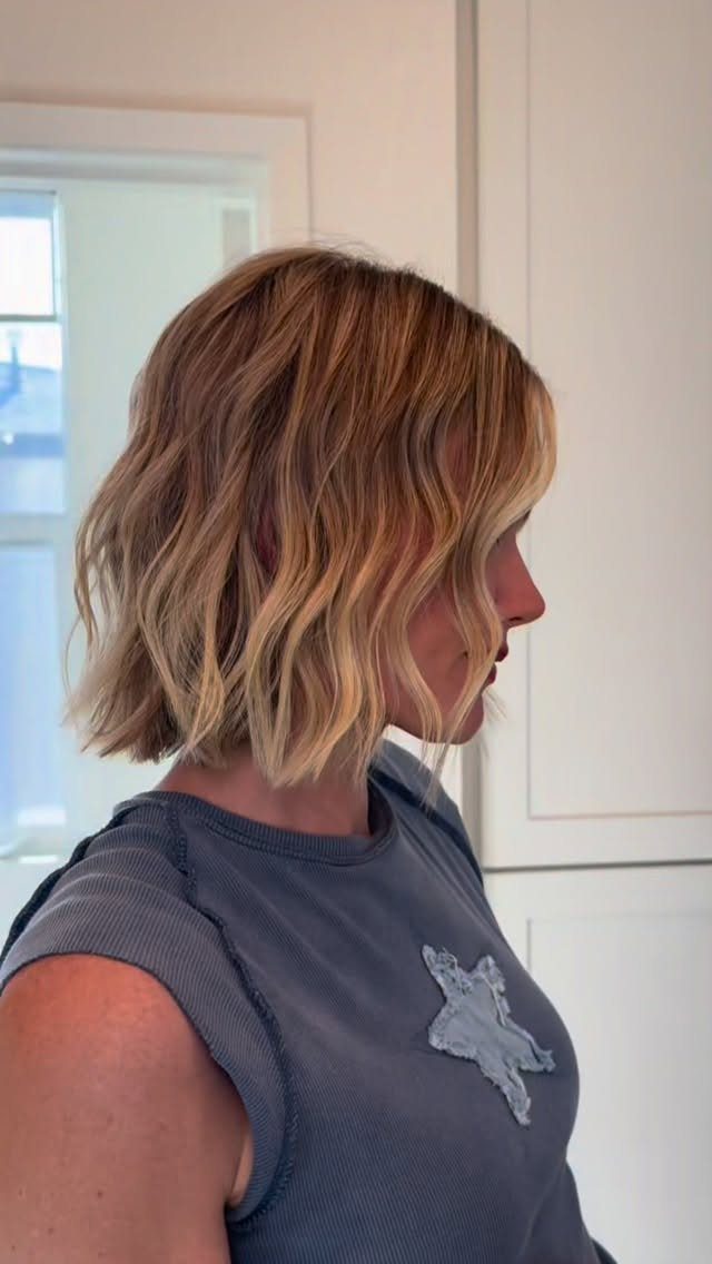 8 Loose Curl Hair Ideas for Blonde, Auburn and Long Looks 5 Woman with blonde shoulder-length hair styled in loose, wavy curls in profile.