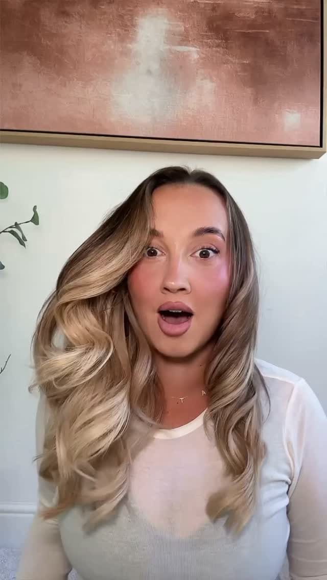 8 Loose Curl Hair Ideas for Blonde, Auburn and Long Looks 6 Woman with long blonde loose curls and a surprised expression wearing white top.