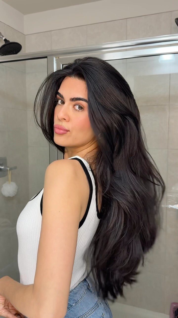 8 Loose Curl Hair Ideas for Blonde, Auburn and Long Looks 3 Woman with long dark hair styled in voluminous loose curls posing in bathroom