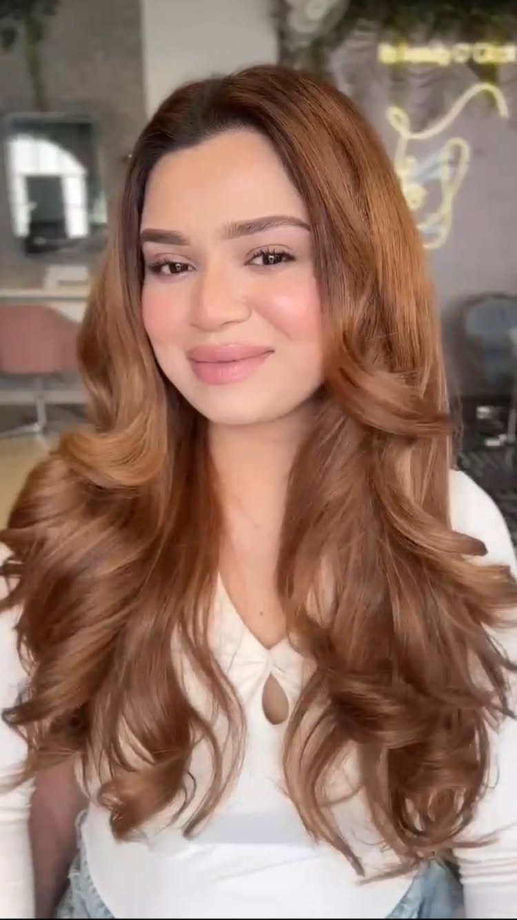 8 Loose Curl Hair Ideas for Blonde, Auburn and Long Looks 4 Woman with long reddish-brown hair styled in voluminous, polished loose curls.