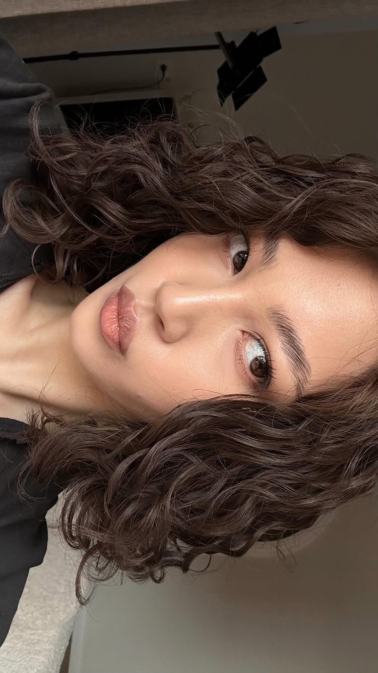 8 Loose Curl Hair Ideas for Blonde, Auburn and Long Looks 8 Woman with dark brown shoulder-length hair styled in loose, voluminous curls.