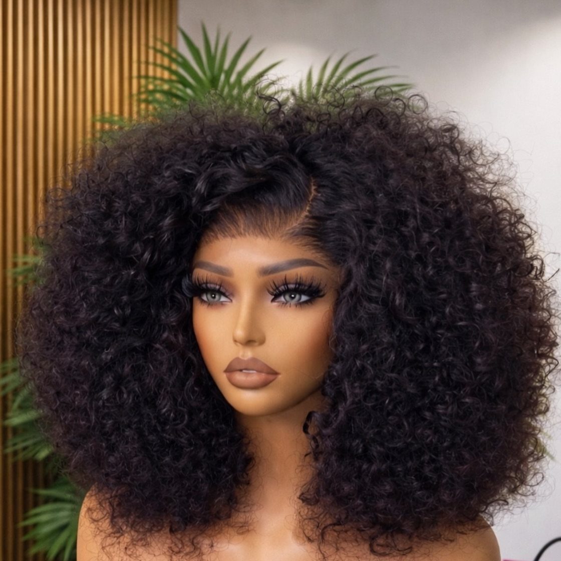 11 Medium Length Curly Hair Hairstyles for Every Look 9 Woman with voluminous medium-length black curly hair and defined coils posing indoors.
