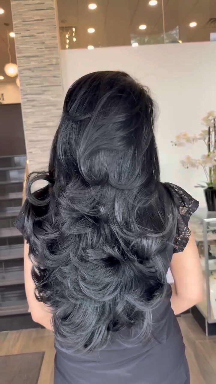 11 Medium Length Curly Hair Hairstyles for Every Look 8 Voluminous dark grey layered hair with bouncy curls seen from the back.