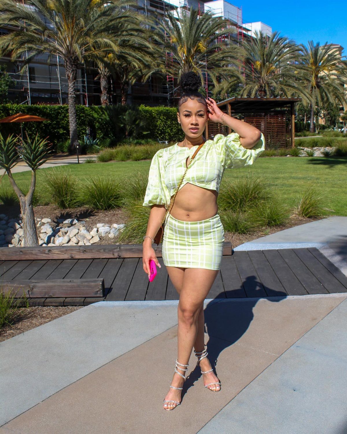 Messy Bun Outfit: 7 Ideas from Jeans to Animal Print 5 Woman with a high messy bun wearing a light green two-piece outfit outdoors.