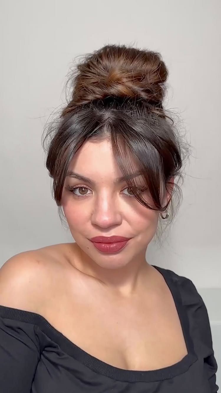 Messy Bun Outfit: 7 Ideas from Jeans to Animal Print 6 Woman with a high messy bun and bangs wearing a black off-shoulder top.