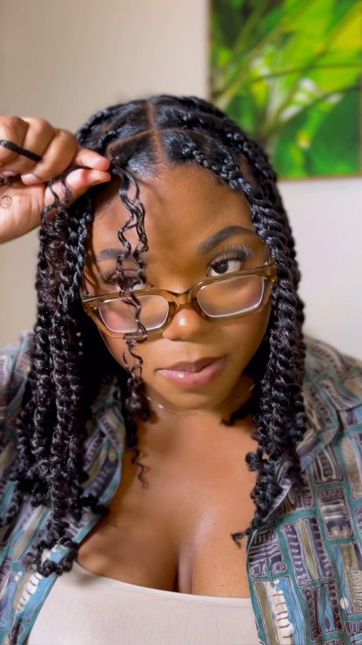 Woman with long black mini twists and glasses posing for a portrait.