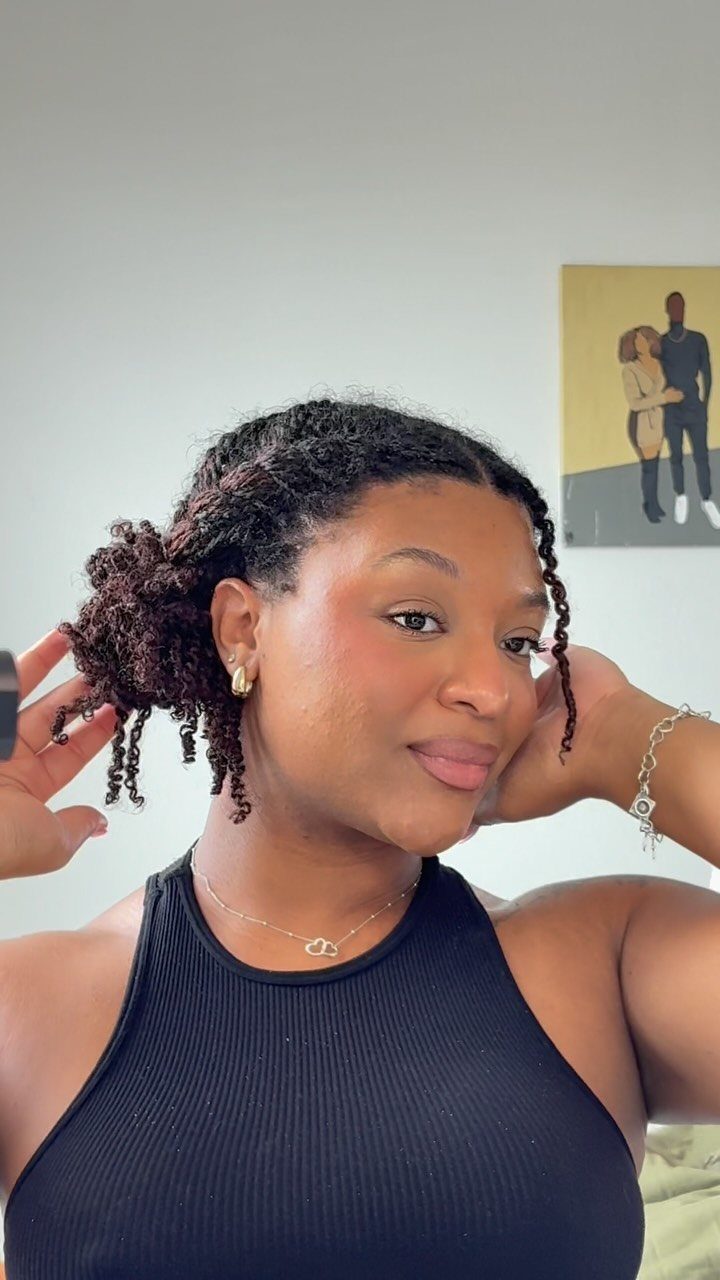 Woman with mini twists styled in a low bun wearing a black top.