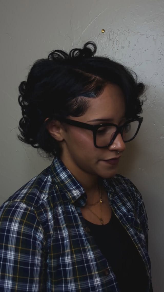 17 Natural Curly Hairstyles for Short Hair You Can Wear 12 Woman with a short curly bixie haircut wearing glasses and a plaid shirt.