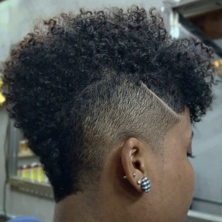 17 Natural Curly Hairstyles for Short Hair You Can Wear 11 Person with a curly mohawk hairstyle featuring shaved sides and a carved line design.