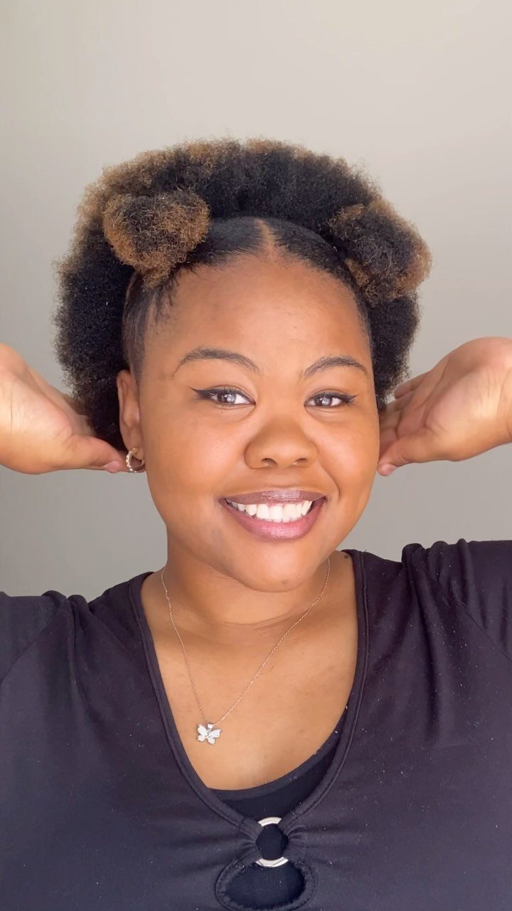17 Natural Curly Hairstyles for Short Hair You Can Wear 14 Woman with short natural curly hair styled in two small puffs smiling.