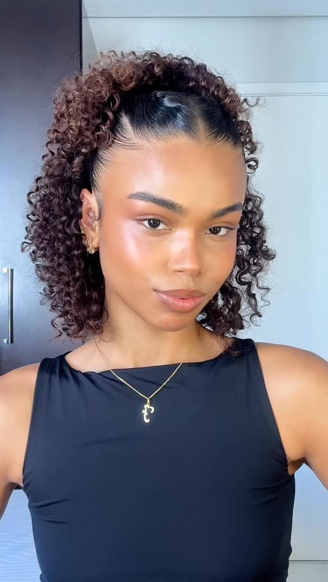 17 Natural Curly Hairstyles for Short Hair You Can Wear 17 Woman with short brown curly hair styled in a half-up ponytail wearing black.