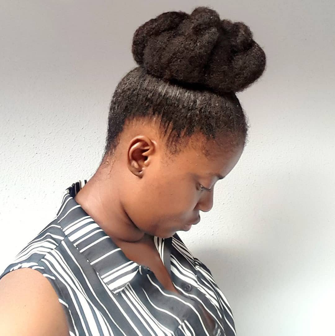 Woman with a large natural hair puff bun and striped sleeveless shirt.
